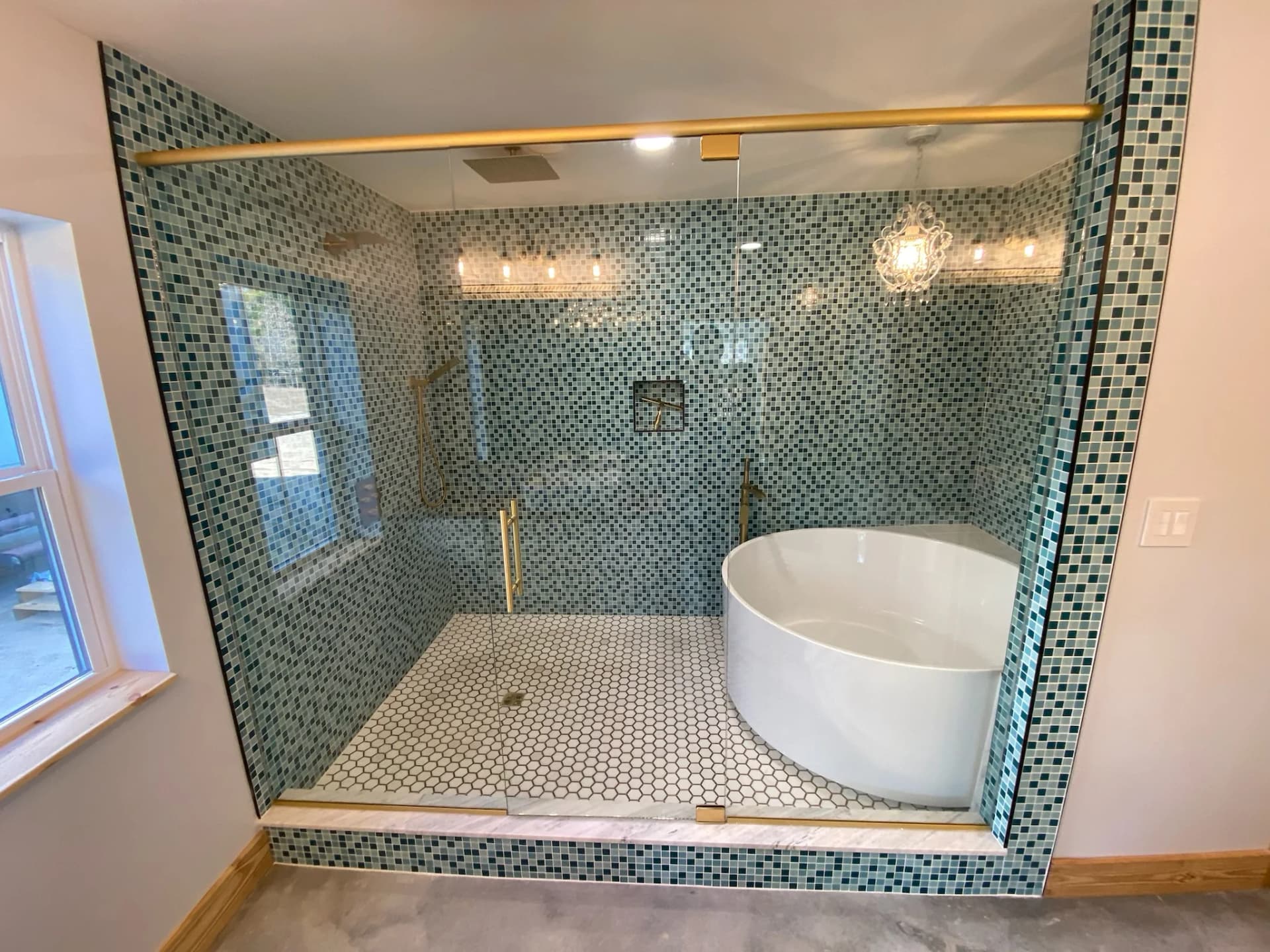 Custom frameless shower glass with blue mosaic tile and brass hardware