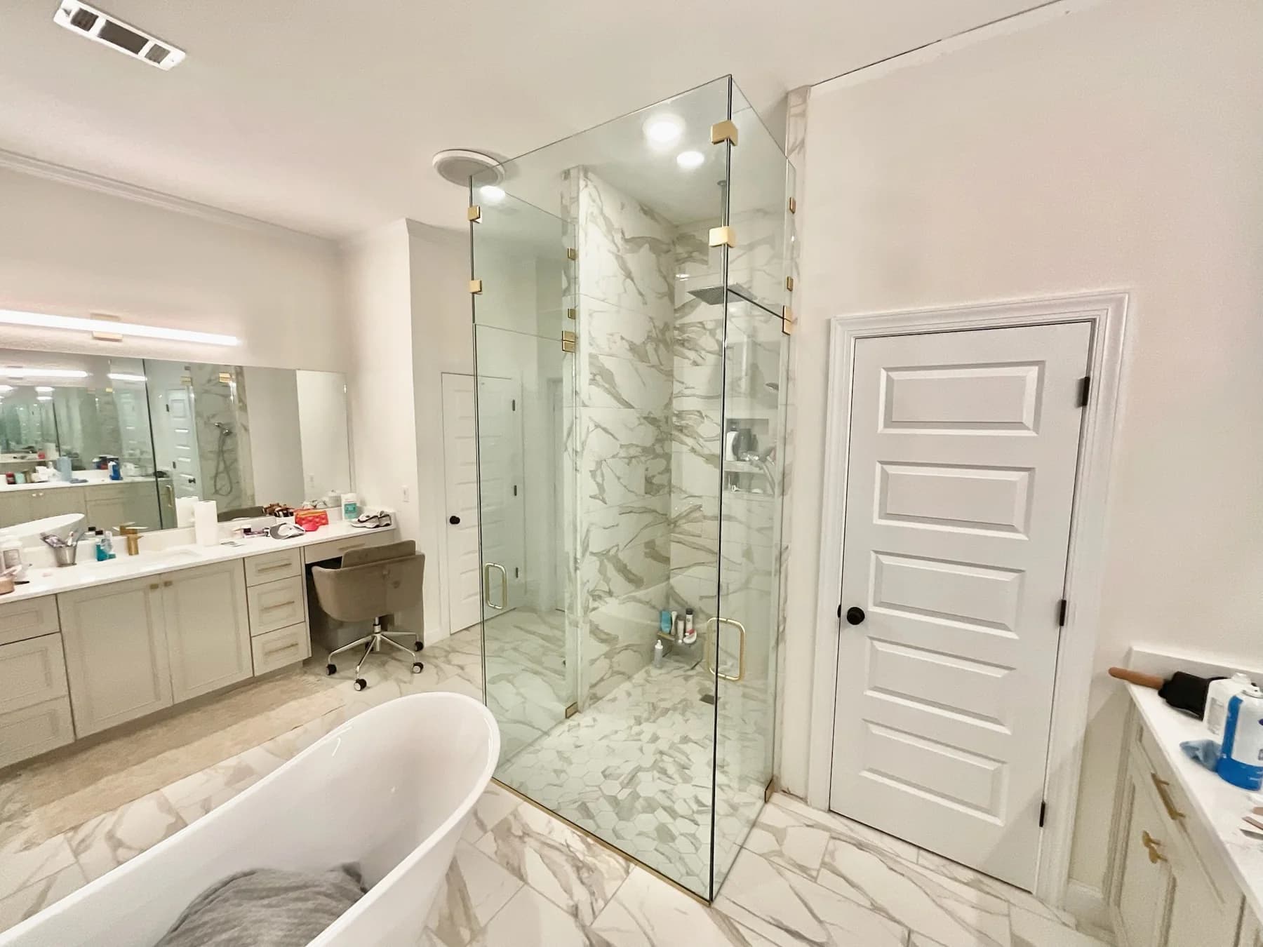 Custom frameless shower glass enclosure with clear panels and brass hardware